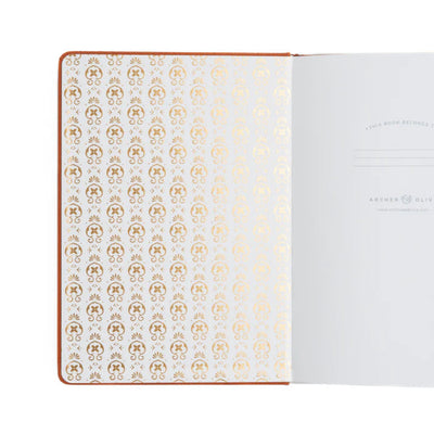 Notebook with gold geometric pattern on white pages, brand 'Anker & Olive' visible.