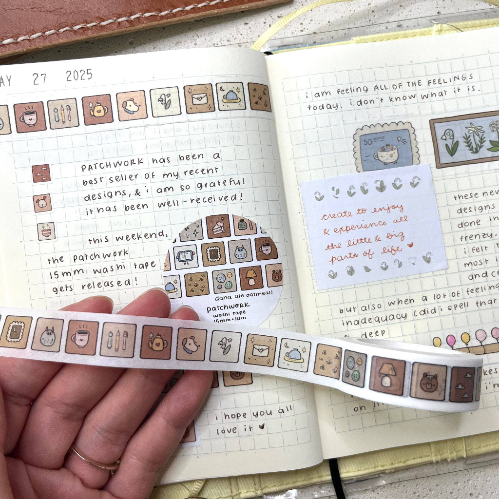 Hand holding a strip of decorative stickers over an open notebook with writing and stickers.