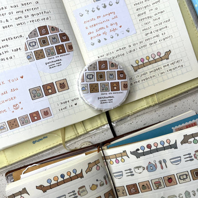 Open notebook with decorative stickers and a circular sticker on a textured surface.