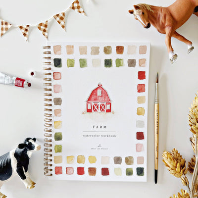 Farm-themed watercolor workbook with a red barn illustration, surrounded by model animals and decor on a white surface.