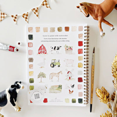 Washable paint book with farm illustrations on a white surface with paint bottles and figurines.