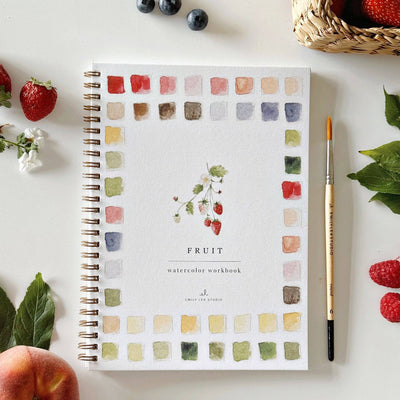 Watercolor workbook titled 'Fruit' with a pen and fruit on a white surface