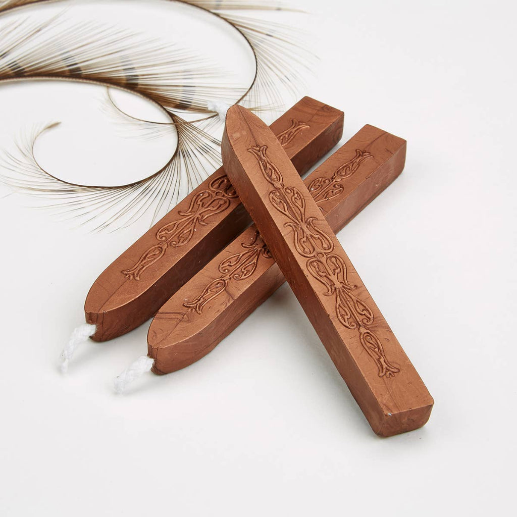 Three wax sticks with intricate carvings on a white background