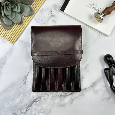 Brown leather pen case from Girologio on a marble surface with a plant and notebook in the background, available at Lighthouse Paper Co. in Melbourne, FL.