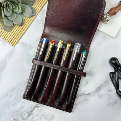 Set of pens in a brown leather pen case from Girologio on a marble surface