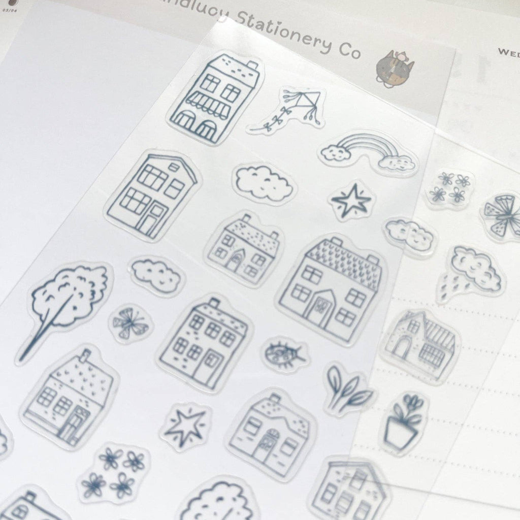 Sheet of black line art stickers featuring houses, trees, and other elements on a white background.