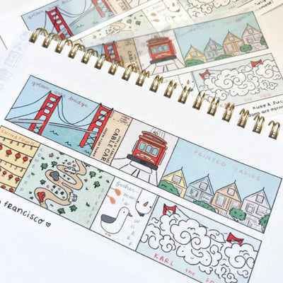 Spiral-bound notebook with illustrated pages featuring landmarks and scenes, on a white background.