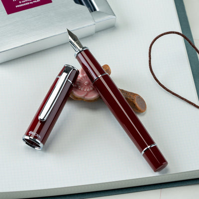 Red fountain pen on a white surface with a blurred background