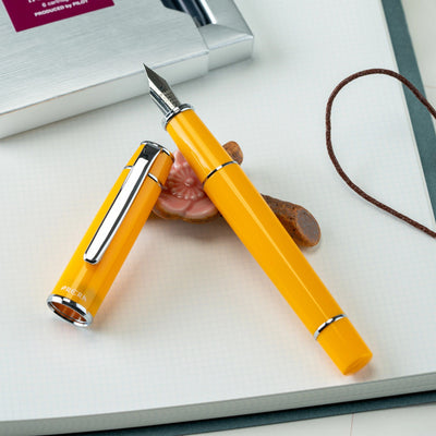 Yellow fountain pen on a white surface with a blurred background