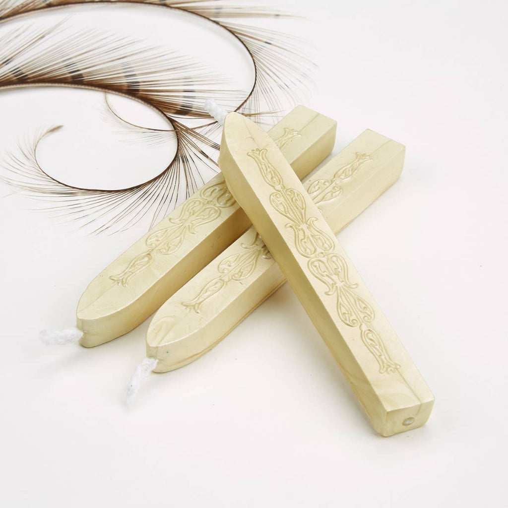 Three wax seal sticks with engraved designs on a white background