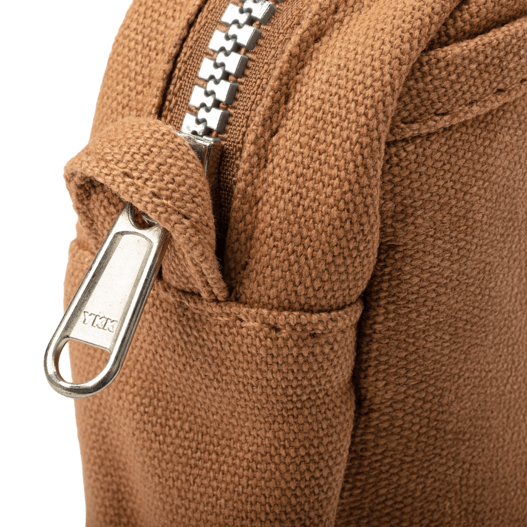 Close-up of a brown textured fabric with a metal zipper and carabiner on a black background