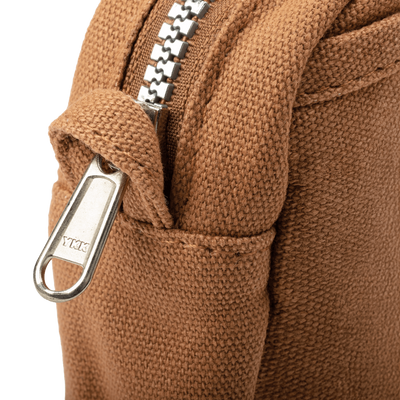 Close-up of a brown textured fabric with a metal zipper and carabiner on a black background
