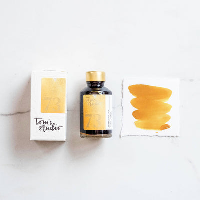 Ink bottle and packaging with 'Tom's Studio' branding on a white background