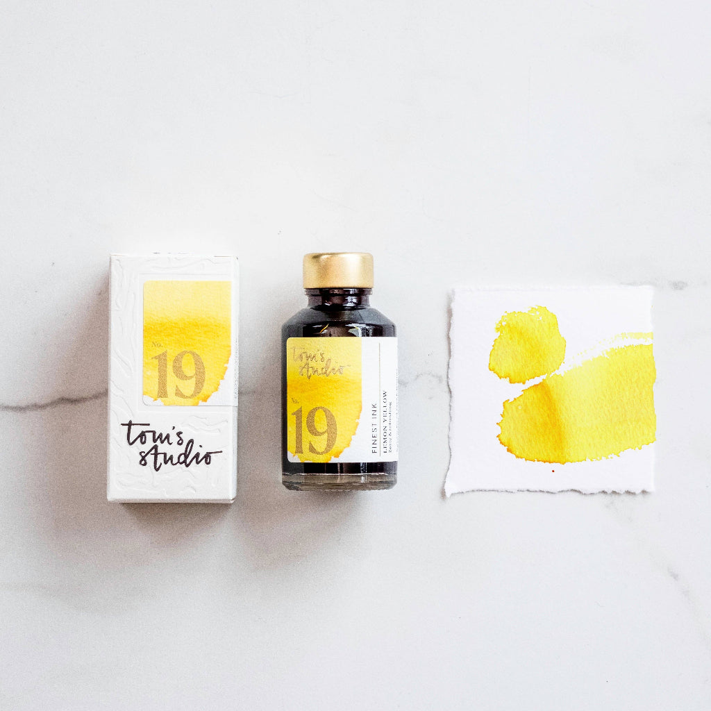 Tom's Studio Lemon Yellow Fountain Pen Ink Bottle and packaging with yellow and black design on a white surface.  Available at Lighthouse Paper Co. in Melboune, FL