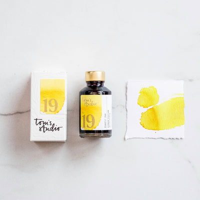 Tom's Studio Lemon Yellow Fountain Pen Ink Bottle and packaging with yellow and black design on a white surface.  Available at Lighthouse Paper Co. in Melboune, FL