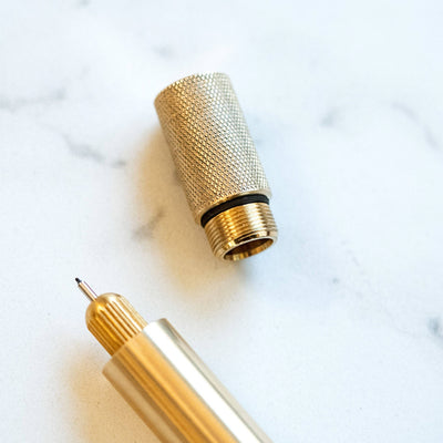 Gold pen with textured cap on a marble surface
