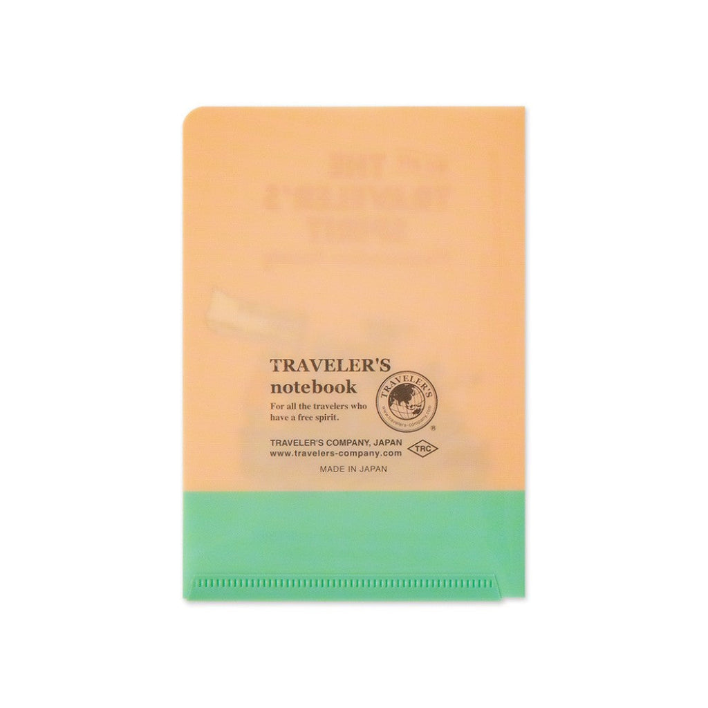 Traveler's notebook with peach top and green bottom on a white background