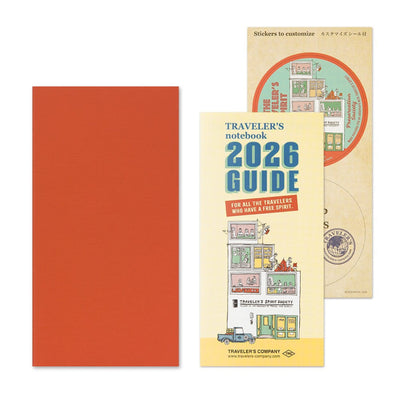 Traveler's notebook set with red cover, yellow guidebook, and small circular item on a white background