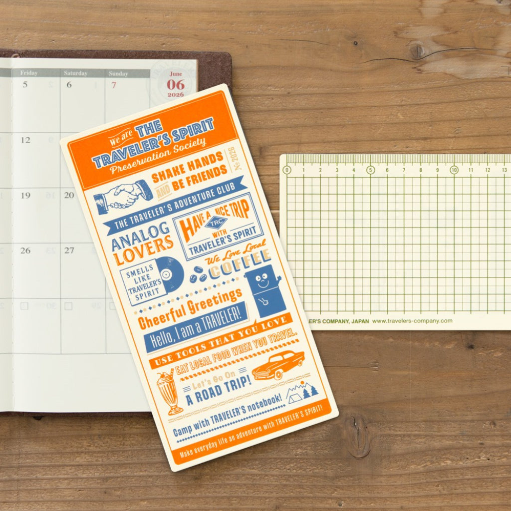 Decorative planner sticker with text on a wooden surface with a planner and grid paper.