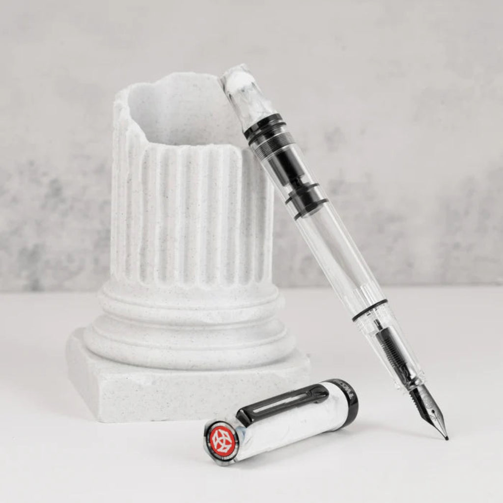 Fountain pen with transparent body and white cap on a marble base