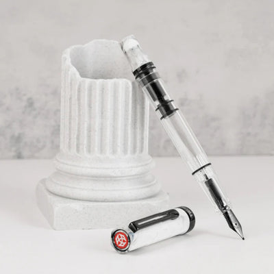 Fountain pen with transparent body and white cap on a marble base