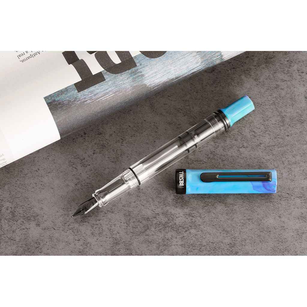 Pen with blue cap and clear body on a gray surface
