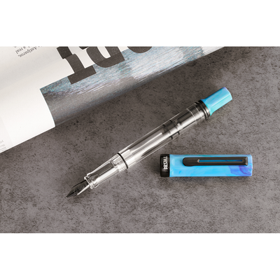 Pen with blue cap and clear body on a gray surface