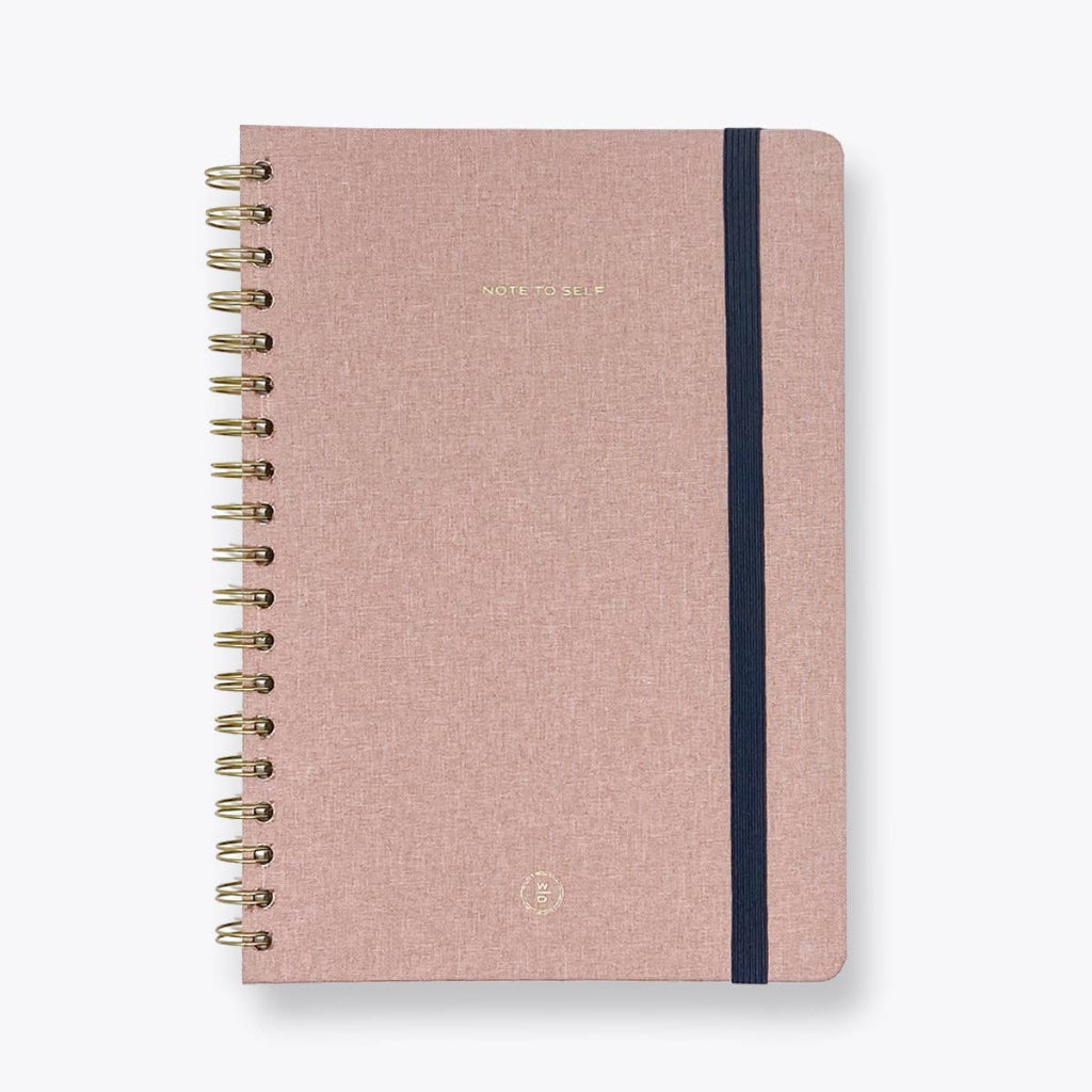 Pink notebook with gold spiral binding on a white background