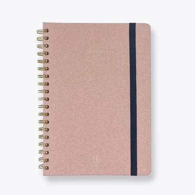 Pink notebook with gold spiral binding on a white background