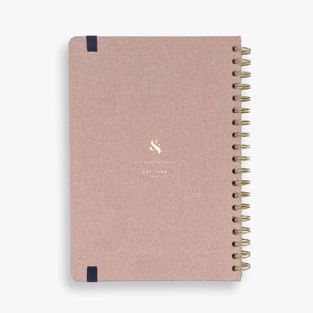 Pink notebook with gold spiral binding on a white background