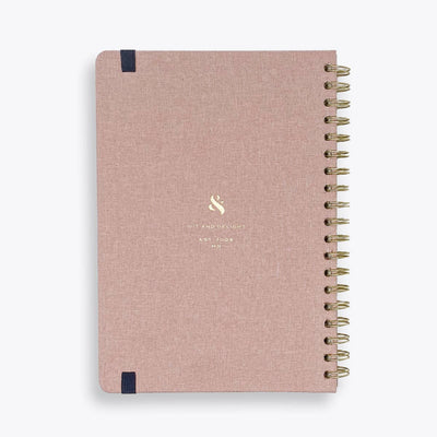 Pink notebook with gold spiral binding on a white background